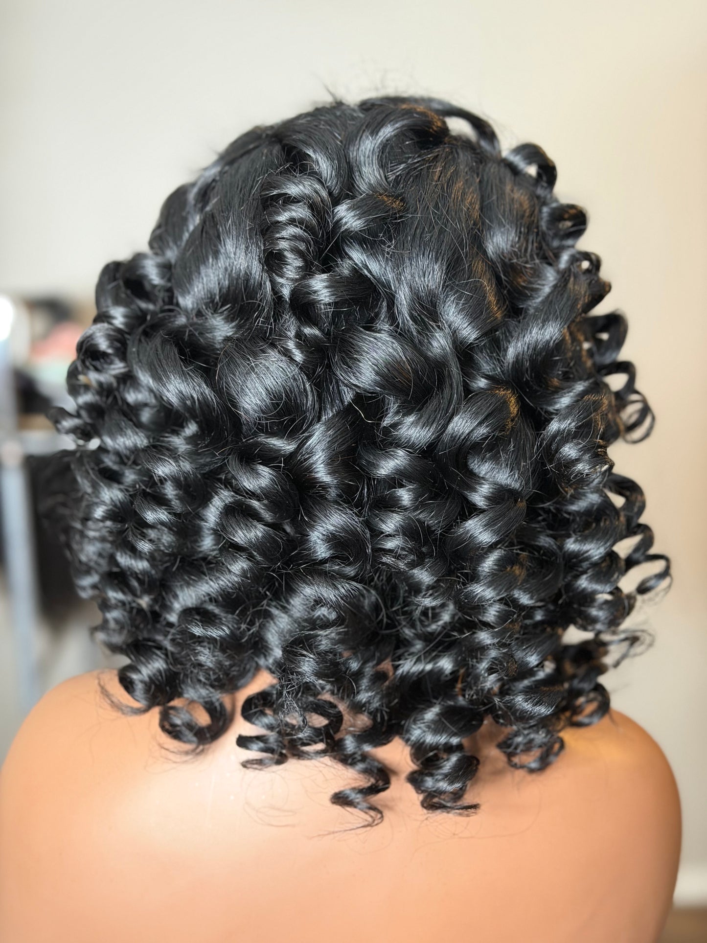 Back view of Naomi highlighting her full-bodied wand curls and elegant shoulder-length silhouette.