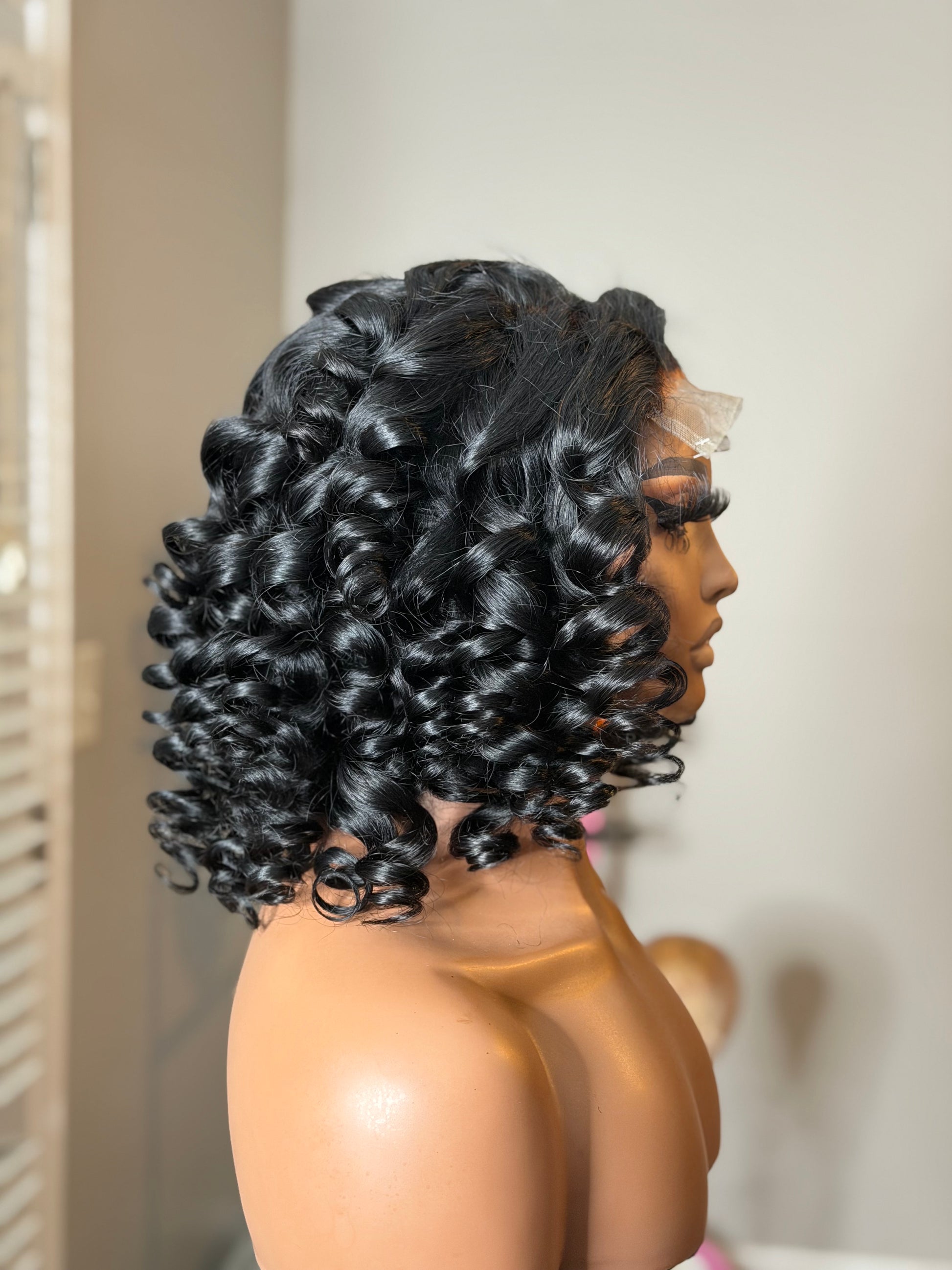 Side profile of Naomi showcasing full wand curls, natural movement, and a glamorous no-part swept-back style.