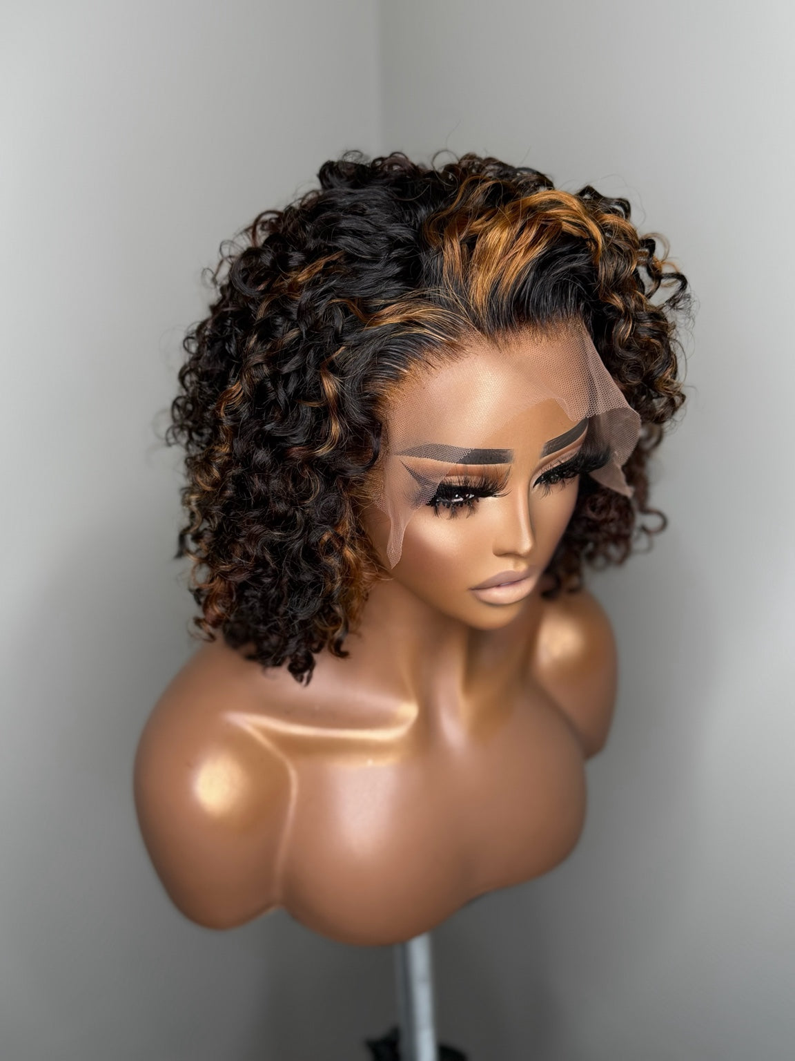 Angled view of Camille curly lace wig showing customized hairline and caramel copper highlights