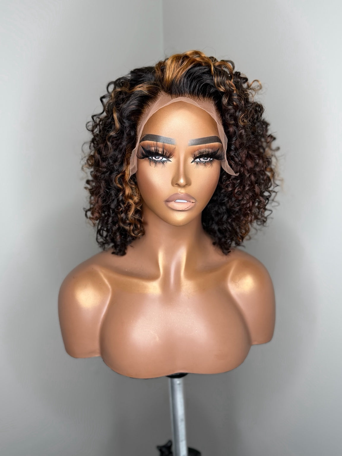 Camille dimensional curly lace wig front view with deep brunette base and warm caramel copper highlights