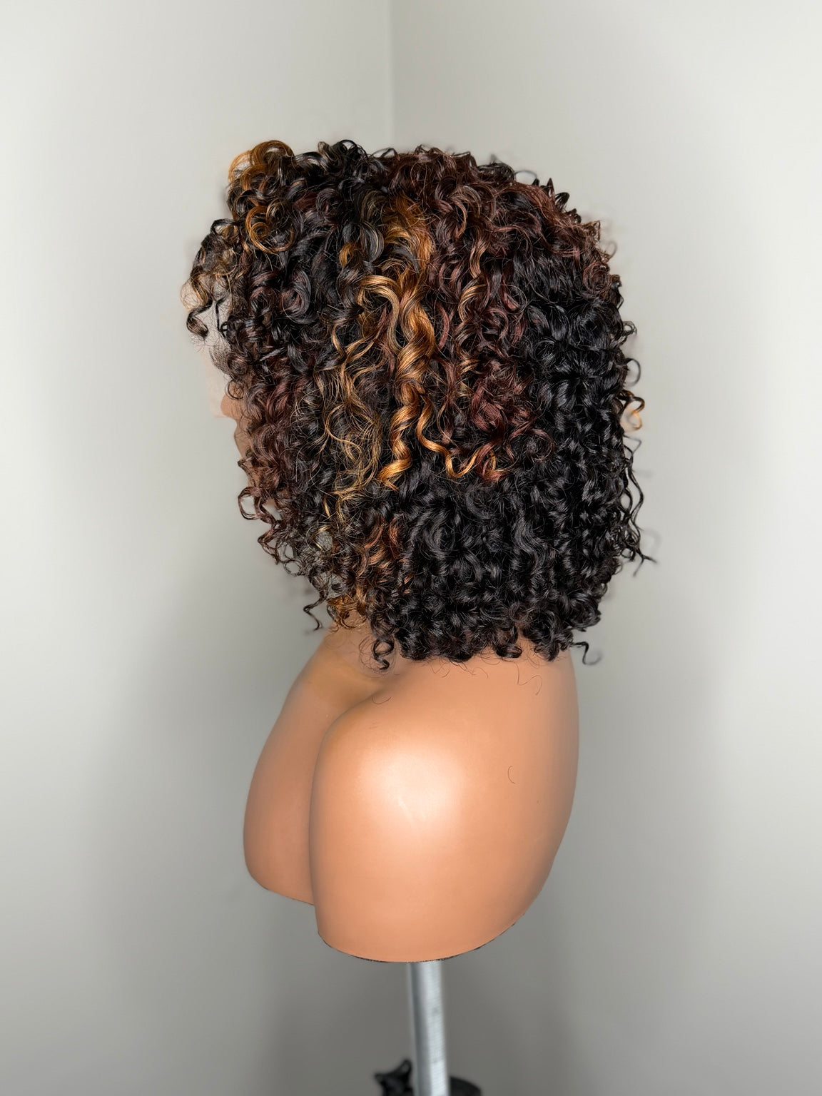 Side view of Camille curly wig showing layered curl shape and dimensional warm highlights