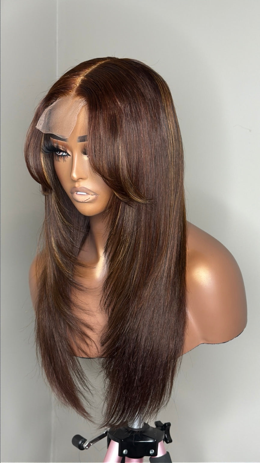 Dimensional brunette human hair wig angled view showing warm highlights and curtain bangs